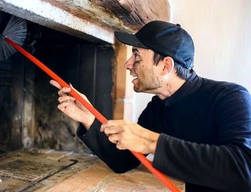 Technician driving a rod-mounted brush up a fireplace flue