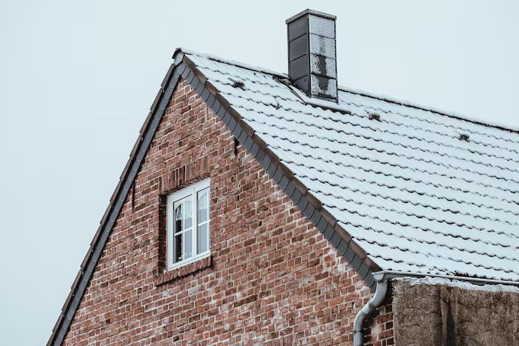 Snow-dusted gable and chimney after a North Shore storm