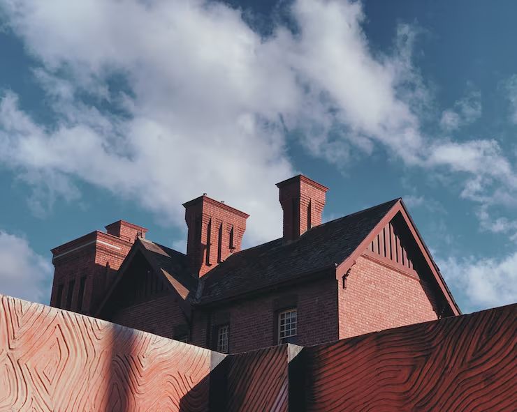Three ornate brick chimney stacks rising over a historic slate roof